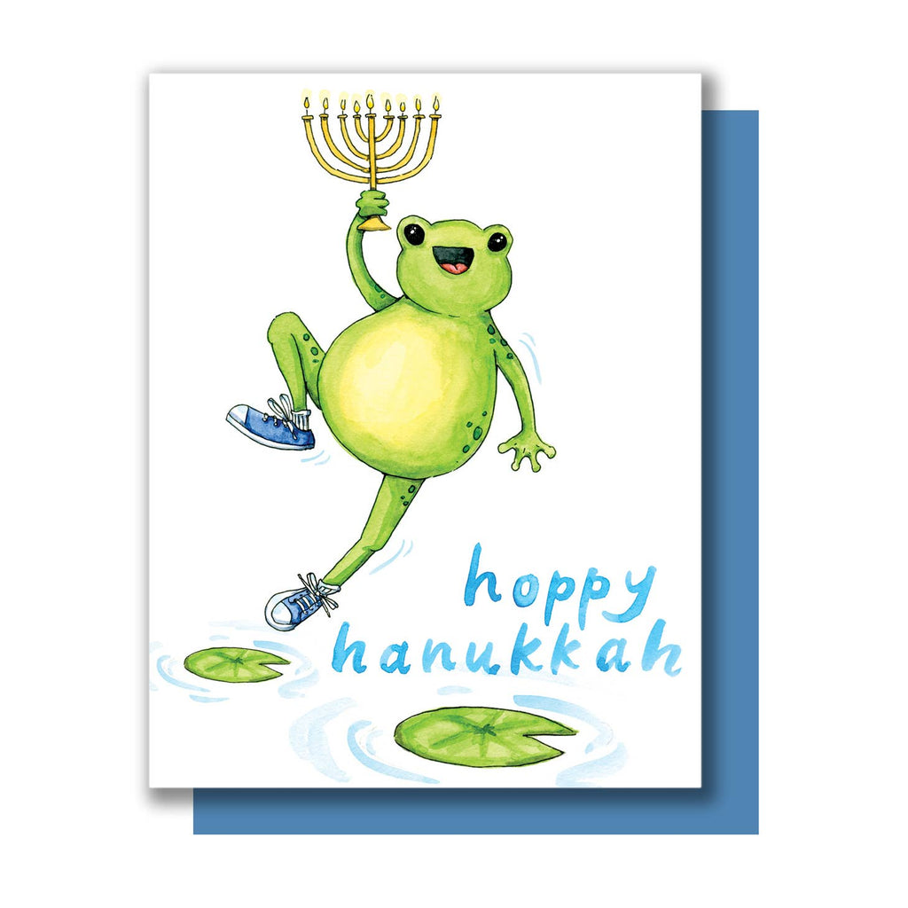 White background with image of green frog wearing blue sneakers and holding a menorah with blue text says, "Hoppy Hanukkah". Blue envelope included.