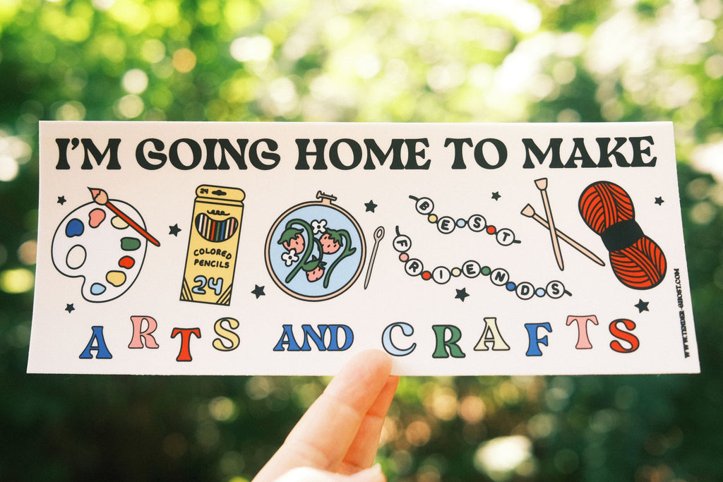 Bumper sticker with images of paint palette, colored pencils, embroidery, beads and knitting with black text says, "I'm going home to make" and rainbow text says, "arts and crafts". 