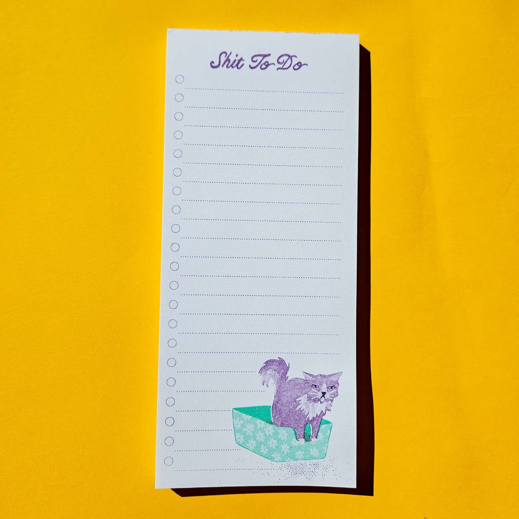 Notepad with image of a lavender cat getting out of an aqua and white flowered litter box in the bottom right corner and lavender text at top says, "Shit to Do" with lavender lines and circle checkboxes on left side. 