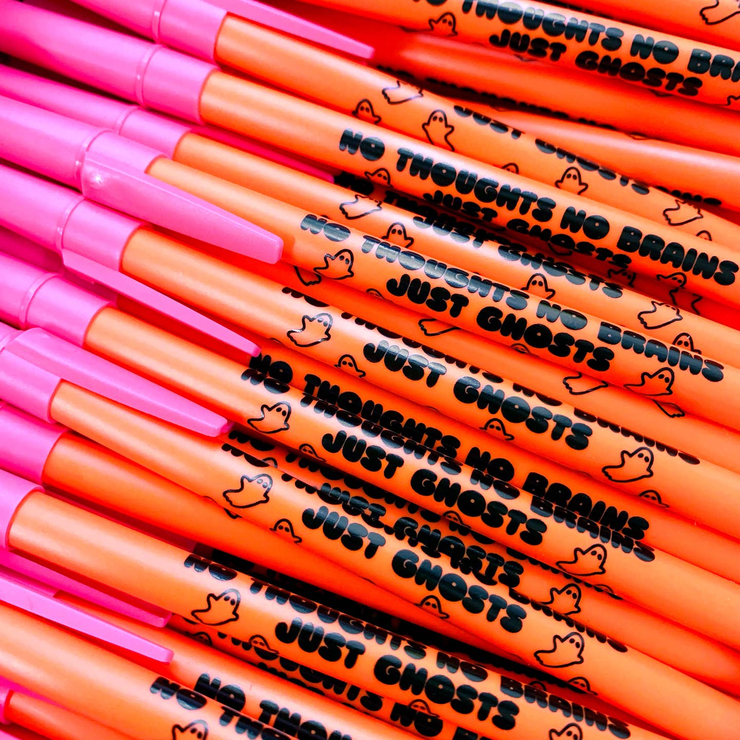 Pen with orange barrel and pink cap. Black text says, "No thoughts, no brains, just ghosts". 