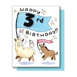 White background with image of a bunny riding on a llama holding a blue banner with a “3rd” on it followed by a brown donkey in a party hat carrying a red banner that says, “Hooray!” and a hamster in a party hat with a banner with a heart on it. Black text says, “Happy birthday”. Blue envelope is included. 