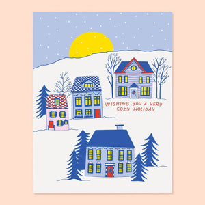 Greeting card set with image of houses in blue, yellow and red on a snowy hillside with yellow moon and red text says, "Wishing you a very cozy holiday". Envelopes included. 