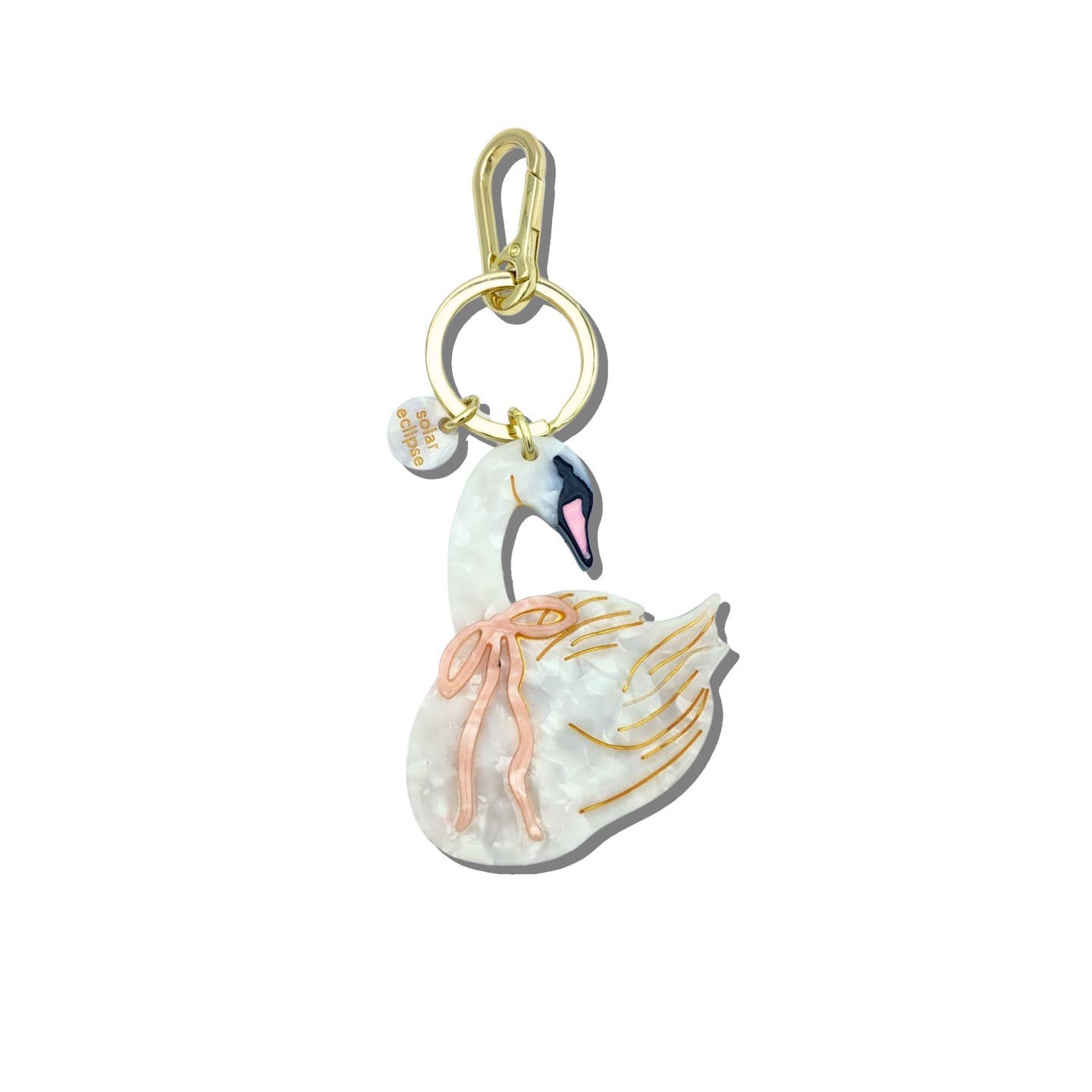 Image of a keychain charm in the shape of a white swan wearing a pink bow around its neck. Gold colored ring and clip. 