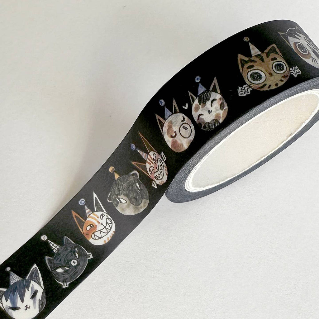 Washi tape with black background and images of cats faces wearing party hats and smiling in tan, white and black. 