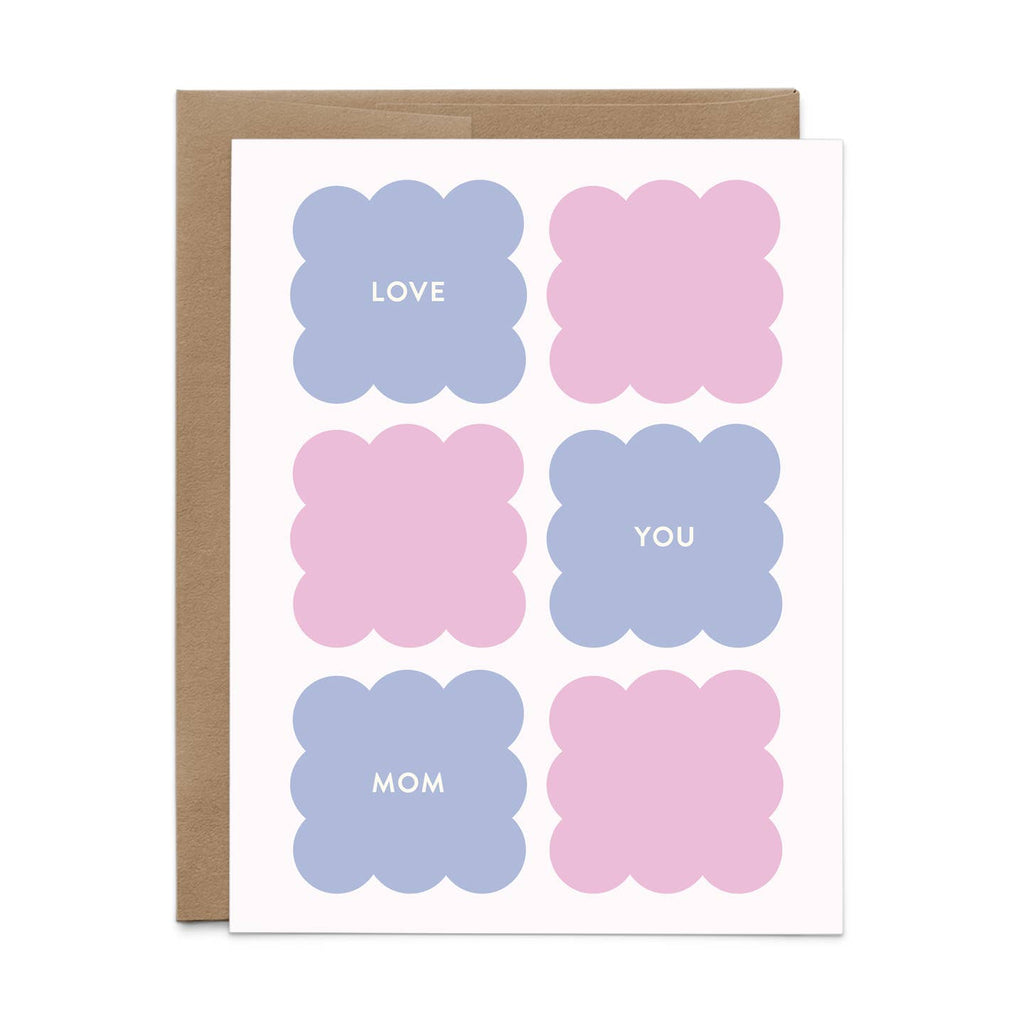 Greeting card with white background and images of scalloped squares in pink and blue with white text says,"Love you Mom". Kraft envelope included. 