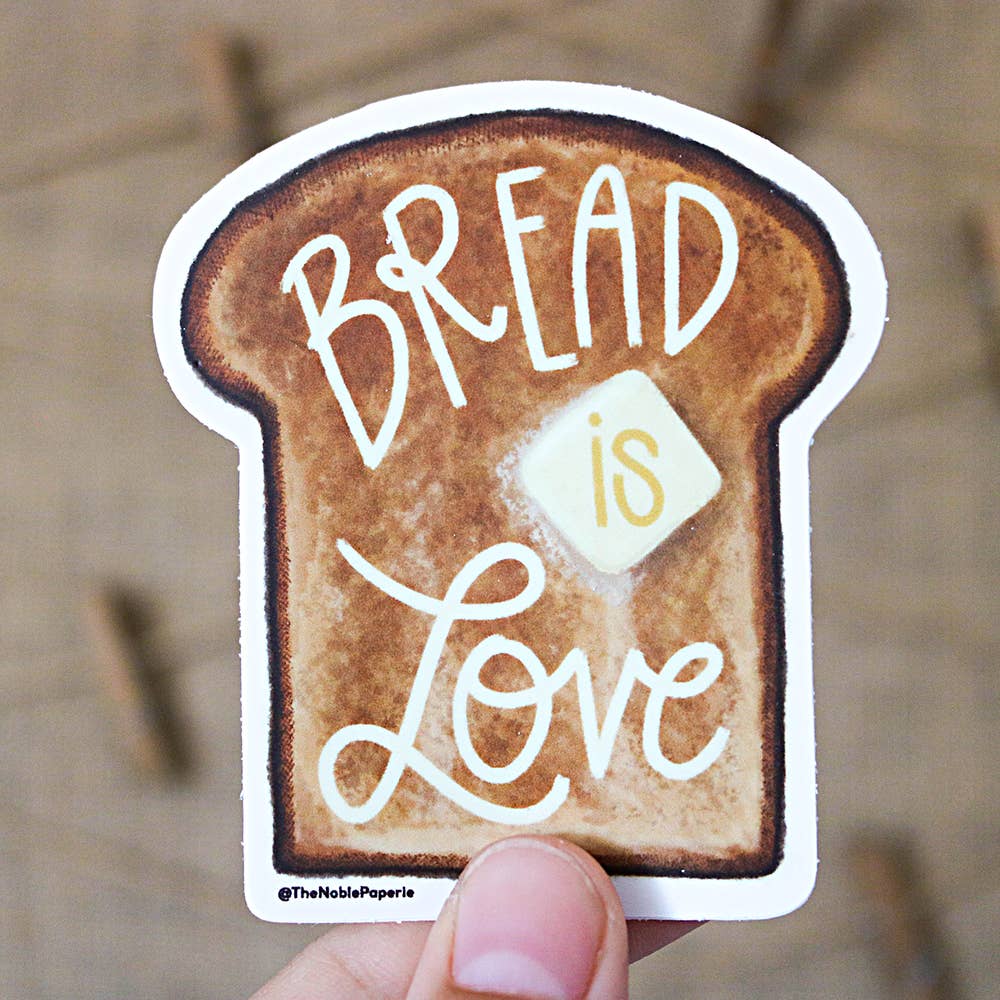 Image of a slice of brown bread with a pat of yellow butter. White text says, “Bread is love”. 