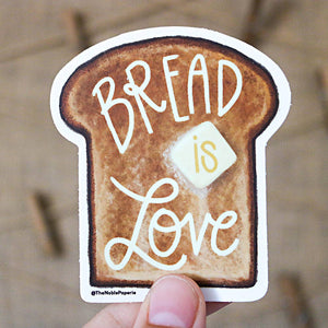 Image of a slice of brown bread with a pat of yellow butter. White text says, “Bread is love”. 