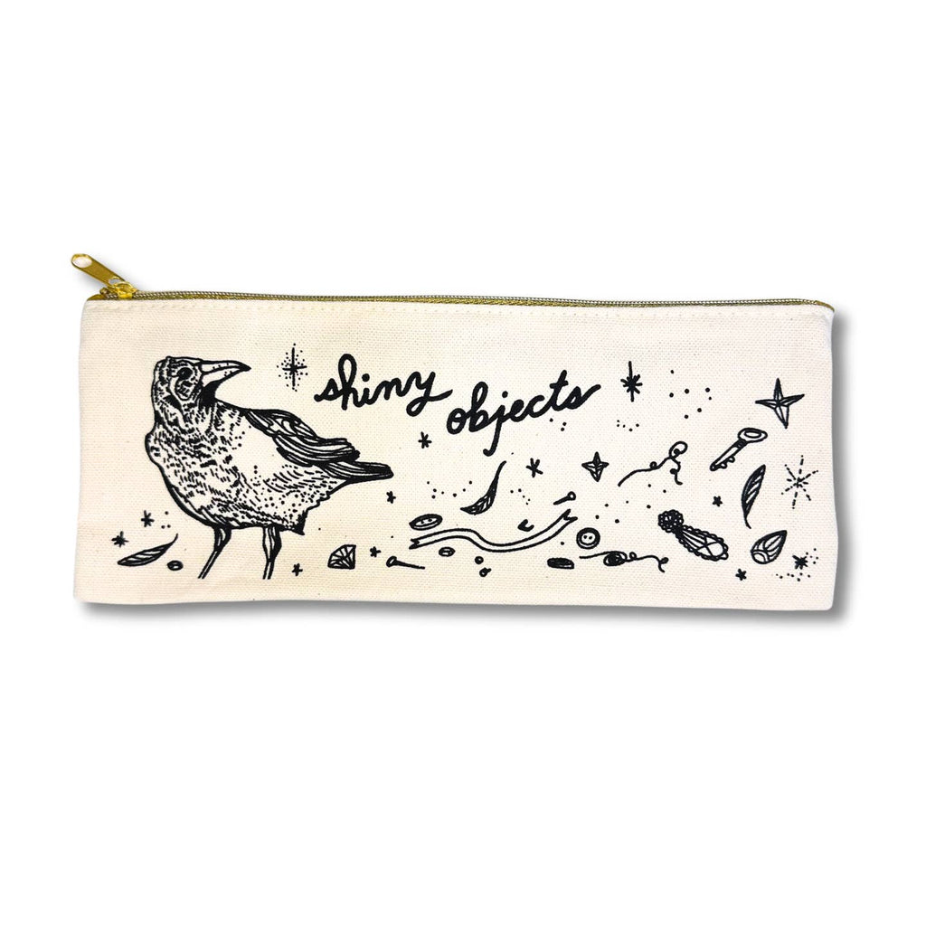 Image of a off white canvas pencil pouch with image of a black crow and many shiny items with black text says, "Shiny objects". 