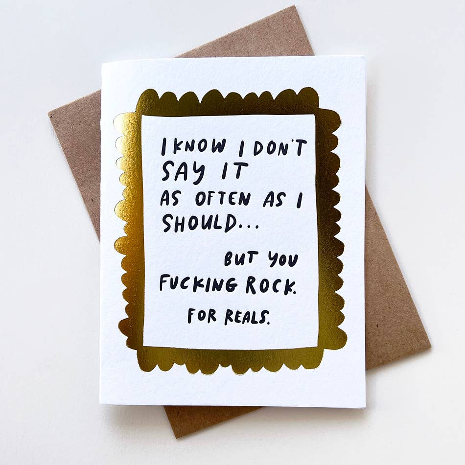 Greeting card with white background and gold foil text says, "I know I don't say it as often as I should... but you fucking rock. For reals." Gold foil scalloped border. Kraft envelope included. 