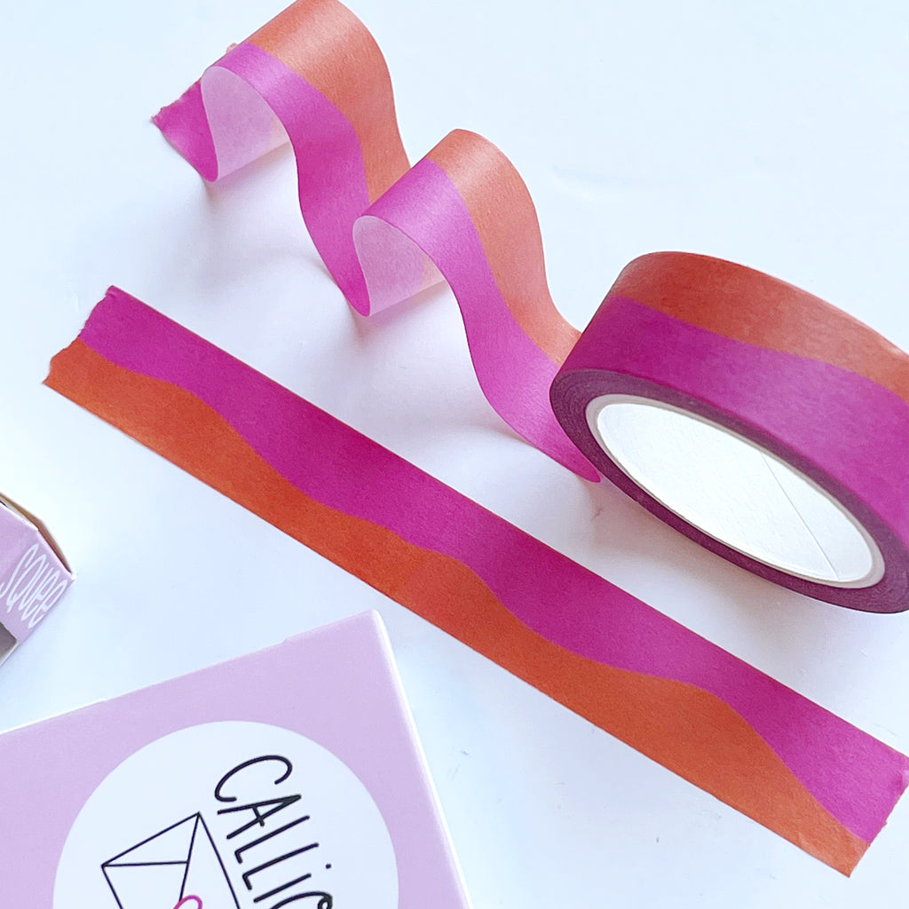 Image of roll of Washi tape with orange and hot pink wavy horizontal lines. 