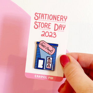 Image of pin with blue building with pink eraser says, "Petite Pearl".