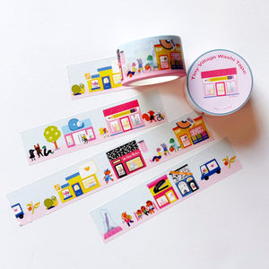 Image of wide washi tape with images of village shops on pink and blue background. 