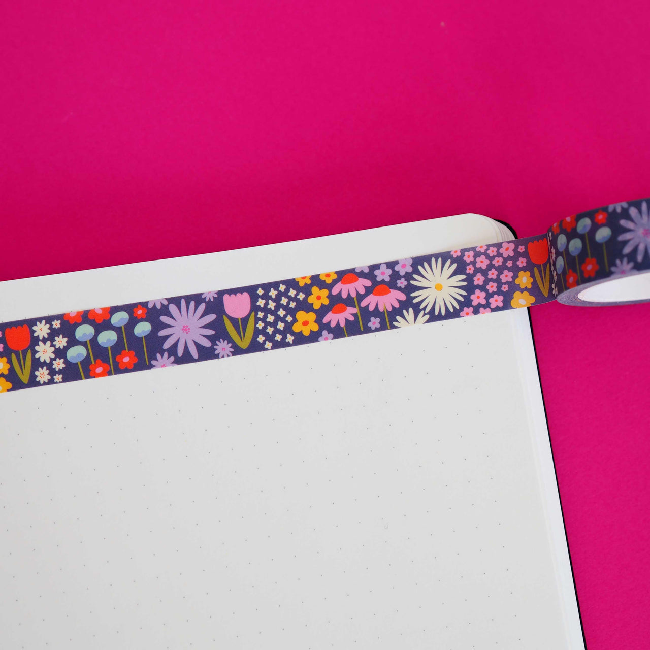 Washi tape with dark blue background and images of wildflowers in white, pink, red, yellow, blue and lilac. 