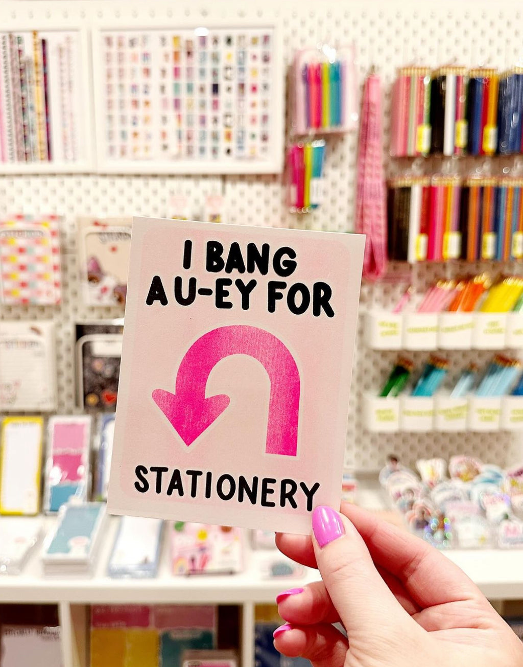 Image of small print with pink background with black text says, "I bang a u-ey for stationery" with a pink arrow in the shape of u turn. 