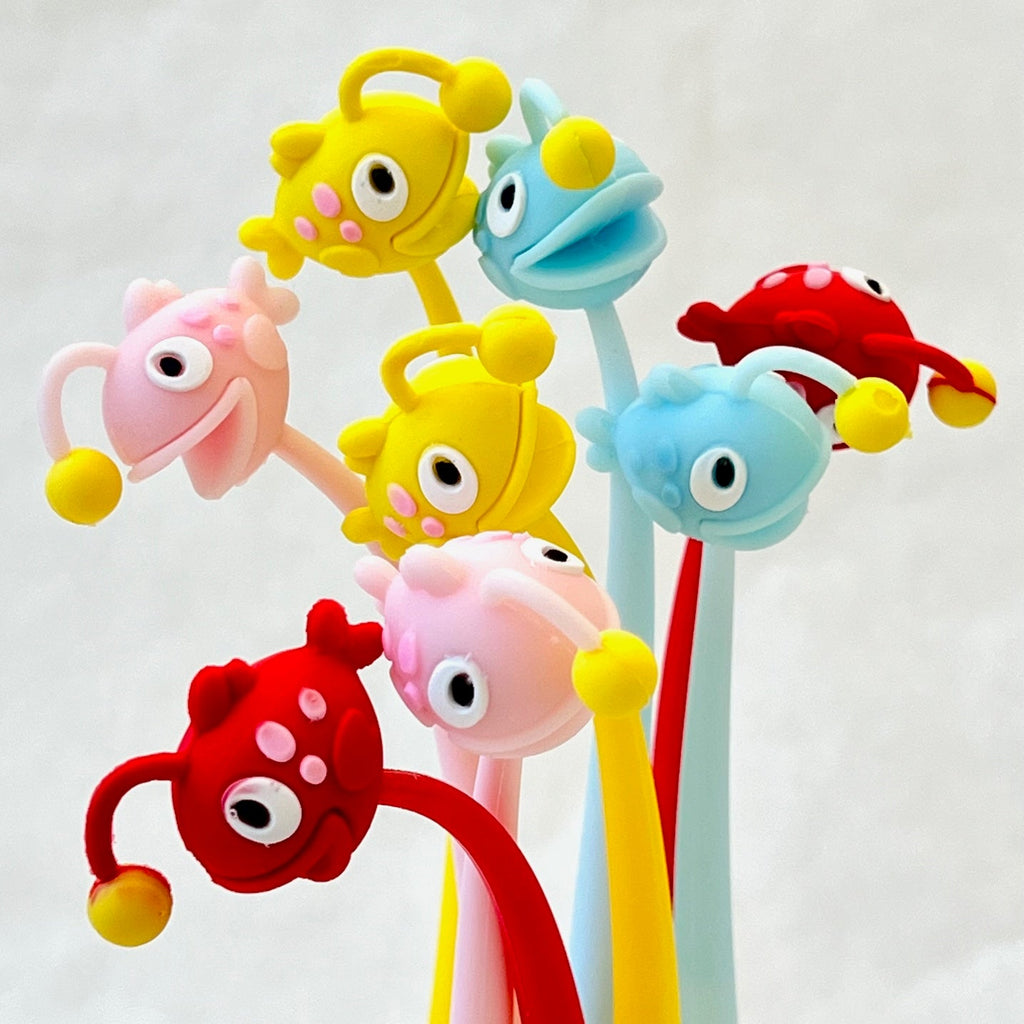 group of 8 pens each with a cute anglerfish at the top. 2 red, 2 pink, 2 yellow, 2 blue. Fish have a smile and cartoon eyes.