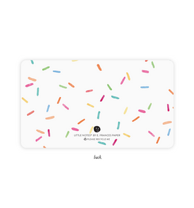 Image of note card with white background with multicolored sprinkles. 