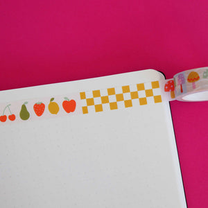 Washi tape with patterns of mustard and white checkerboard, fruits including cherries, pear, strawberry, lemon and apple and toadstools in red, green, pink, and lilac.