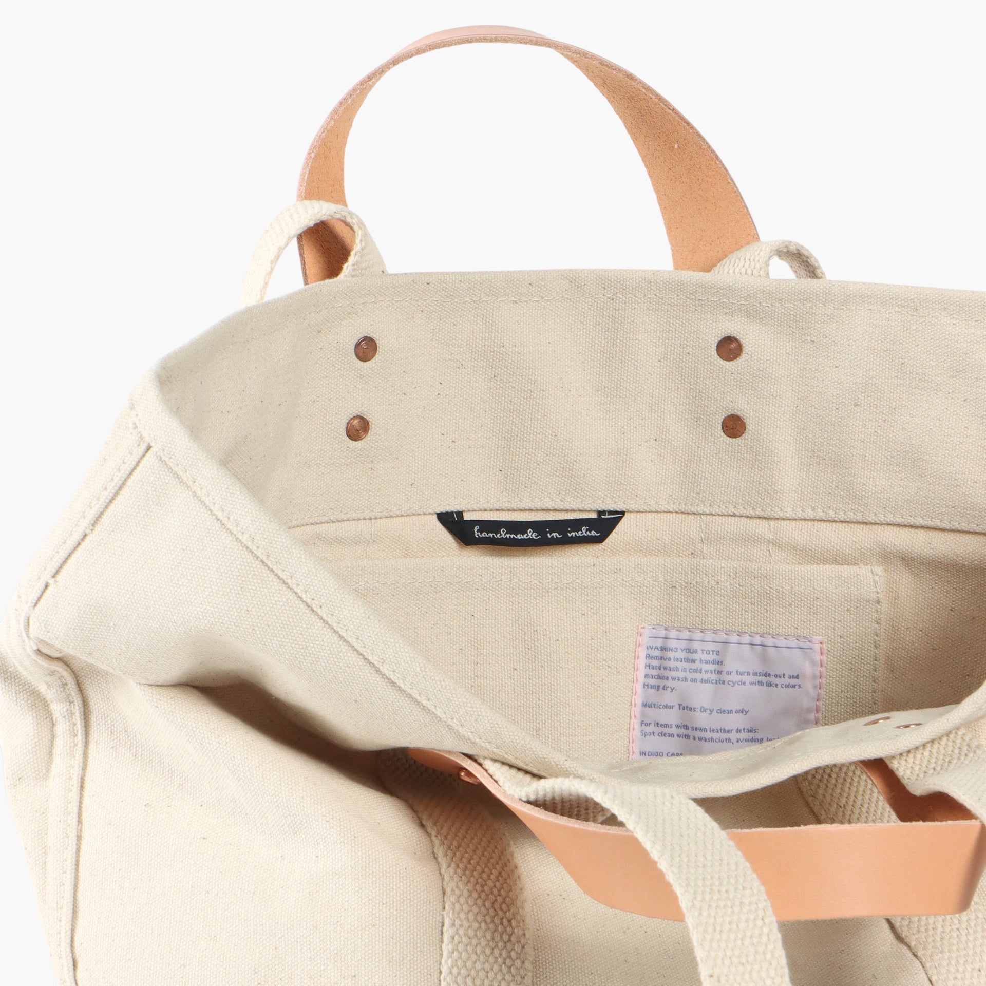 Ivory tote bag with short leather handles and longer ivory webbing handles.