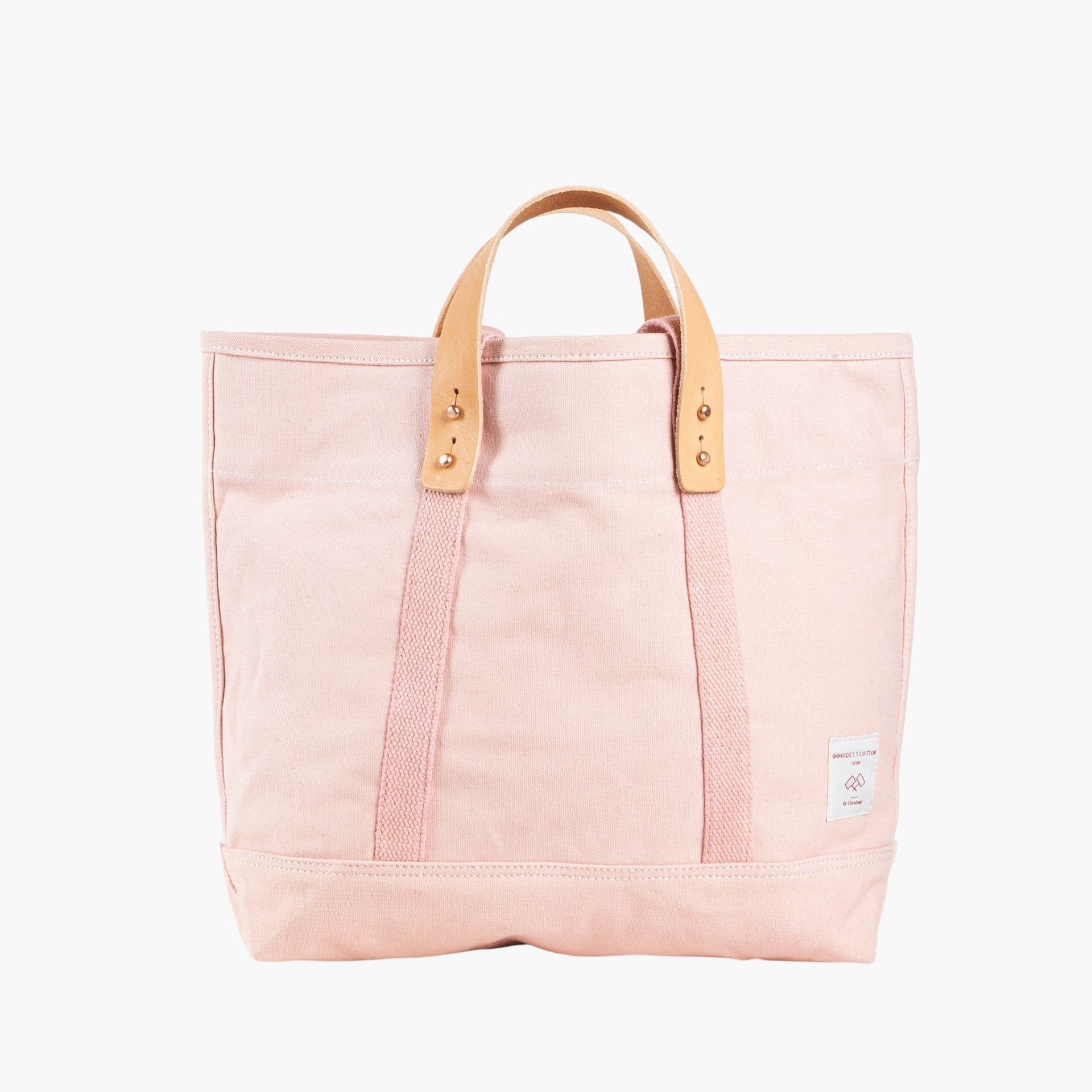 Pink tote bag with short leather handles and longer pink webbing shoulder straps. 