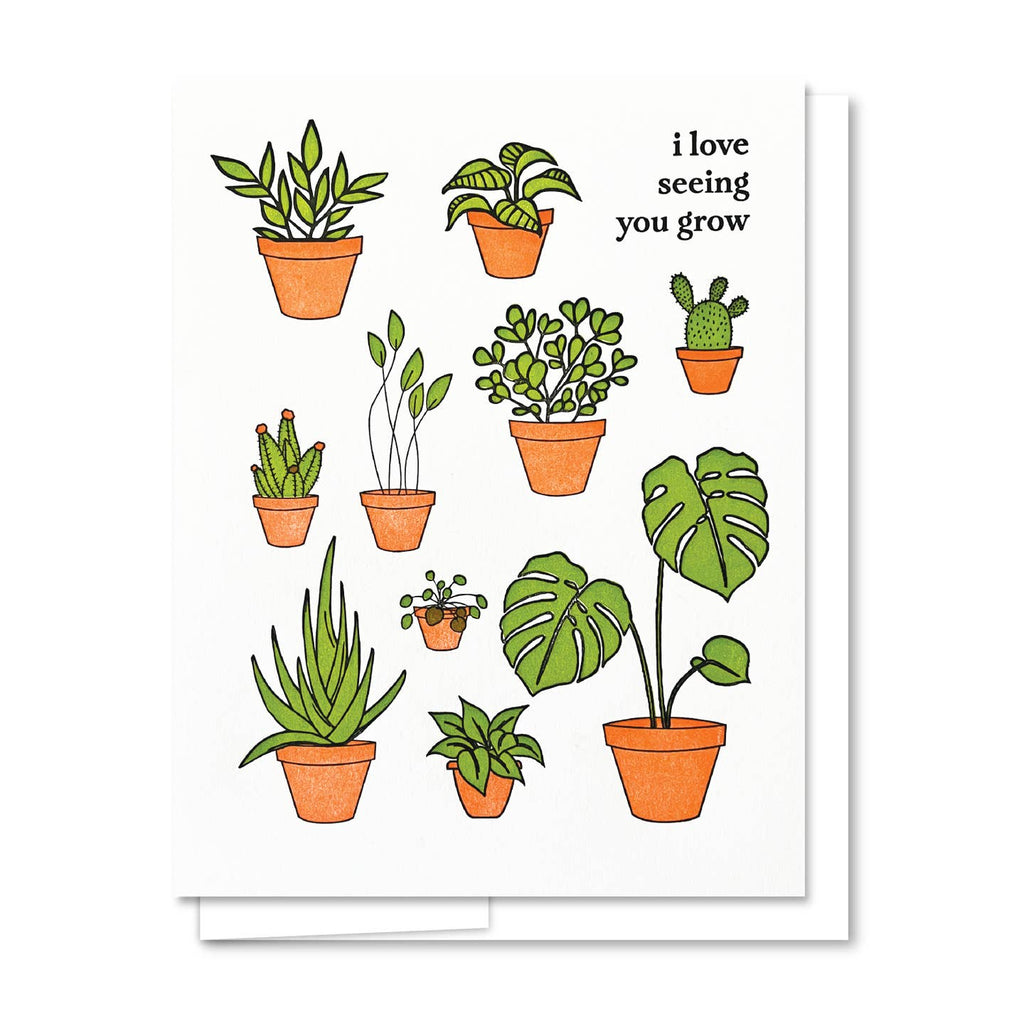 Greeting card with white background and image of potted plants in green and terracotta pots with black text says, "I love seeing you grow". White envelope included. 