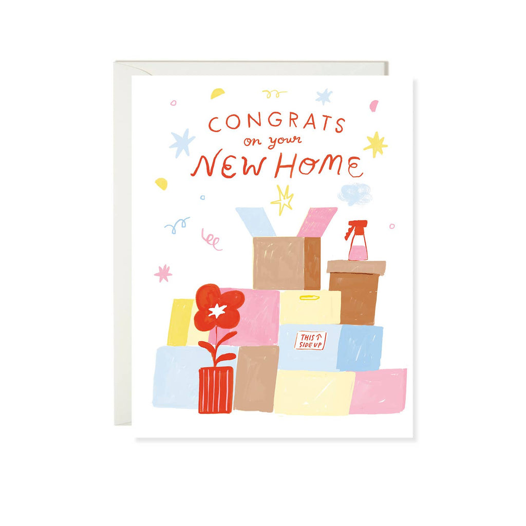 Greeting card with white background and image of brown, pink, blue and yellow boxes with a red potted plant and red text says, "Congrats on your new home". Envelope included. 