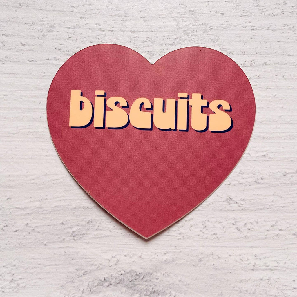 Heart shaped decorative sticker with red background and tan text says, " Biscuits". 