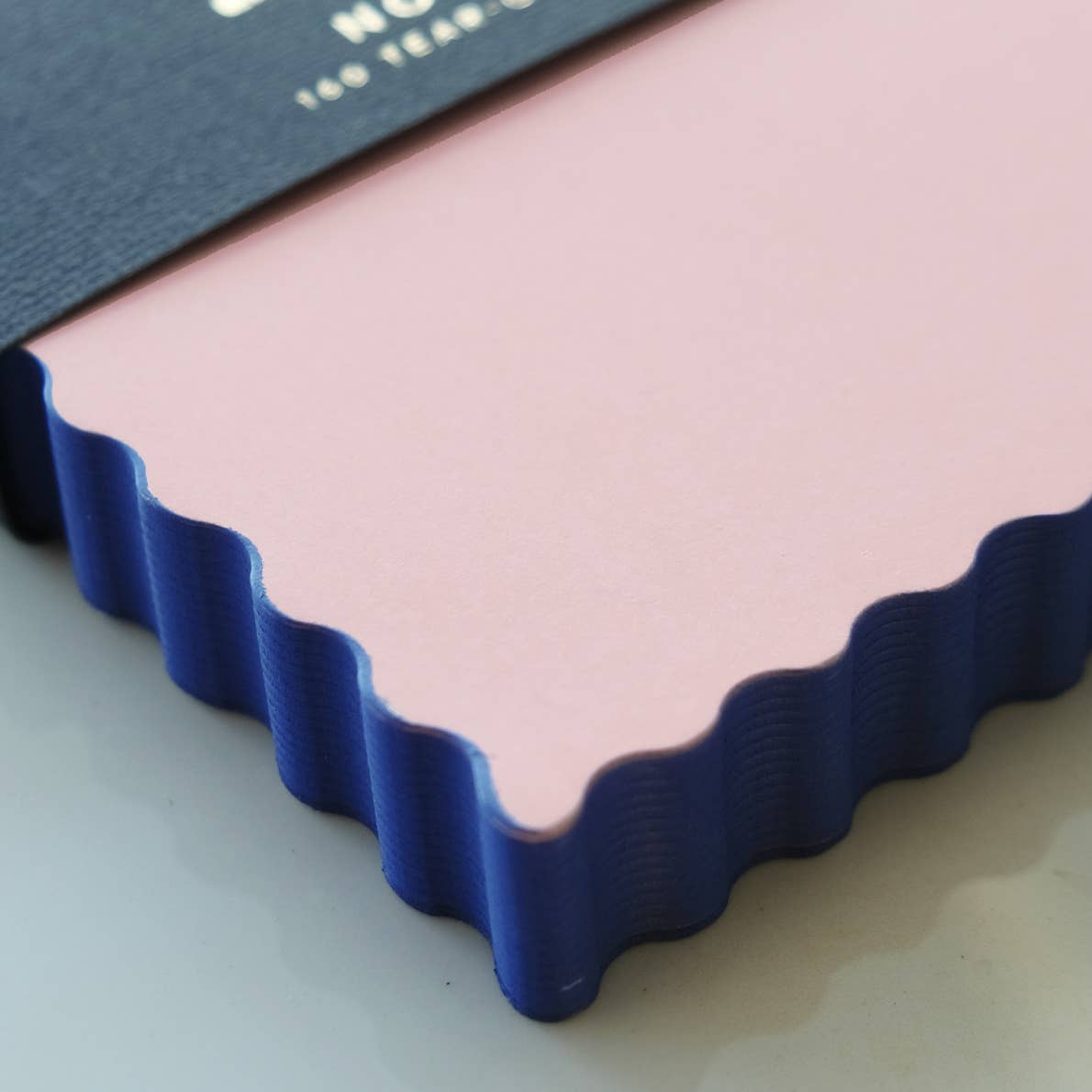 Notepad with peach paper and indigo wavy edging.