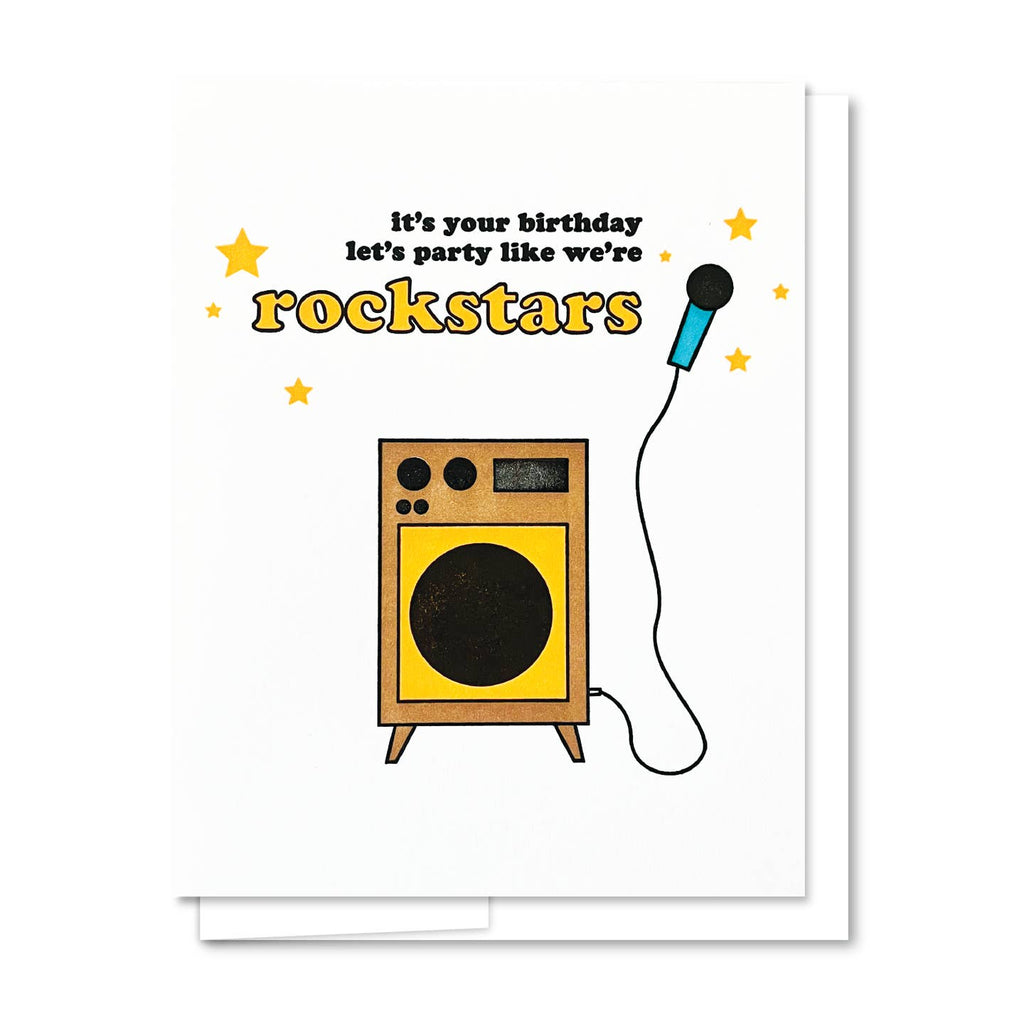 Greeting card with white background and image of a karaoke machine and microphone with black text says, "It's your birthday, let's party like we're" and yellow text says, "Rockstars". White envelope included. 