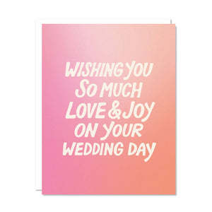 Greeting card with pink and peach background and white text says, "Wishing you so much love & joy on your wedding day". White envelope included.