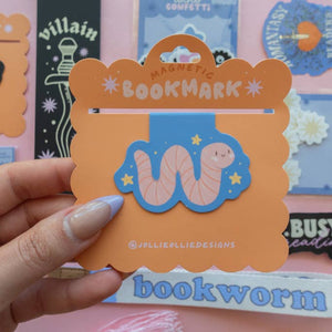 Magnetic bookmark with image of a pink worm on a blue background with yellow stars. 