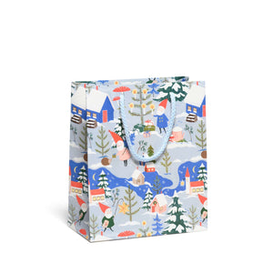 Gift bag with pale blue background and images of gnomes decorating trees and and houses in blue, red and green. 