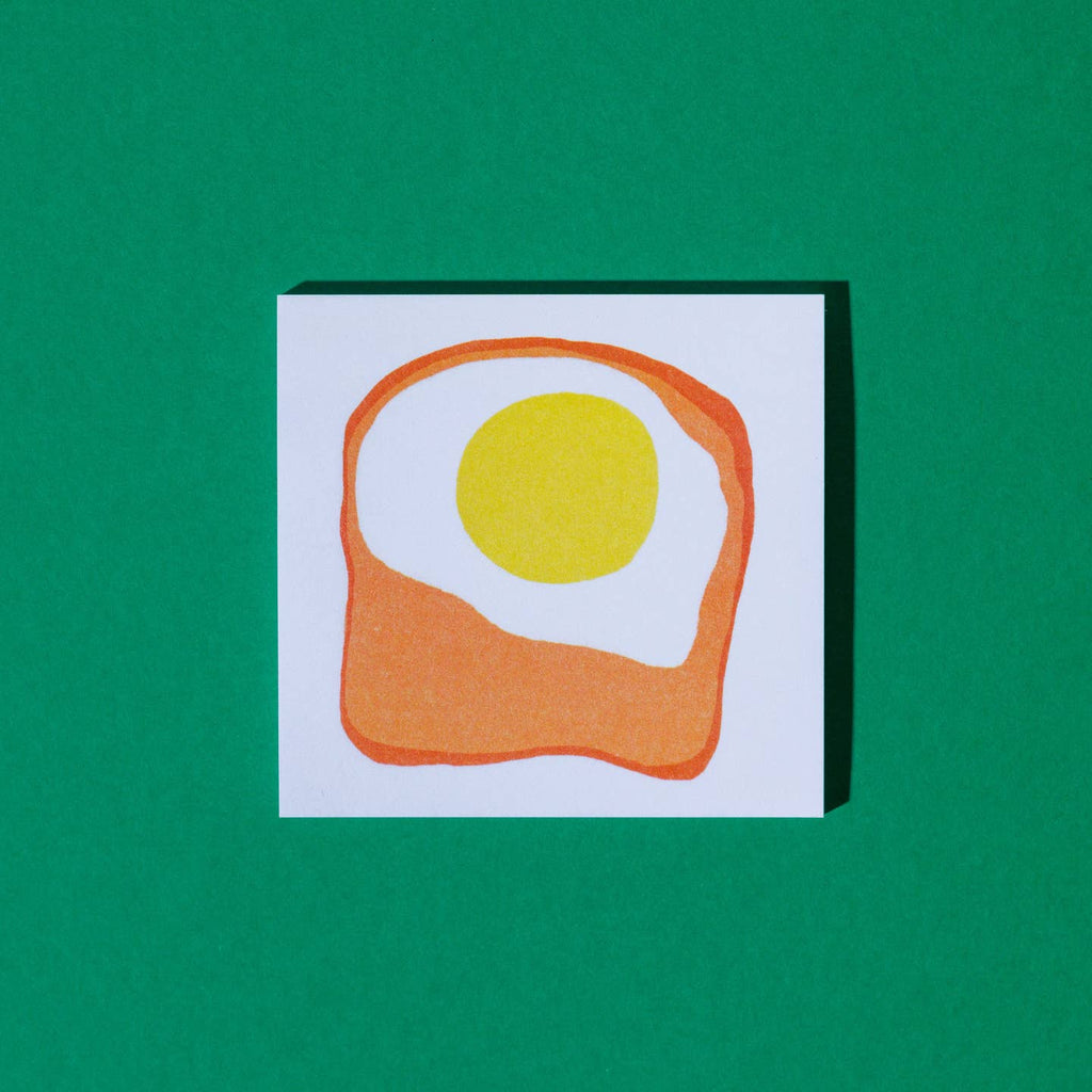 Sticky notepad with white backgrund and image of a fried egg on toast in center.
