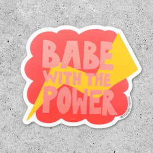 Decorative sticker with orange background with yellow lightening bolt and pink text says, "Babe with the power". 