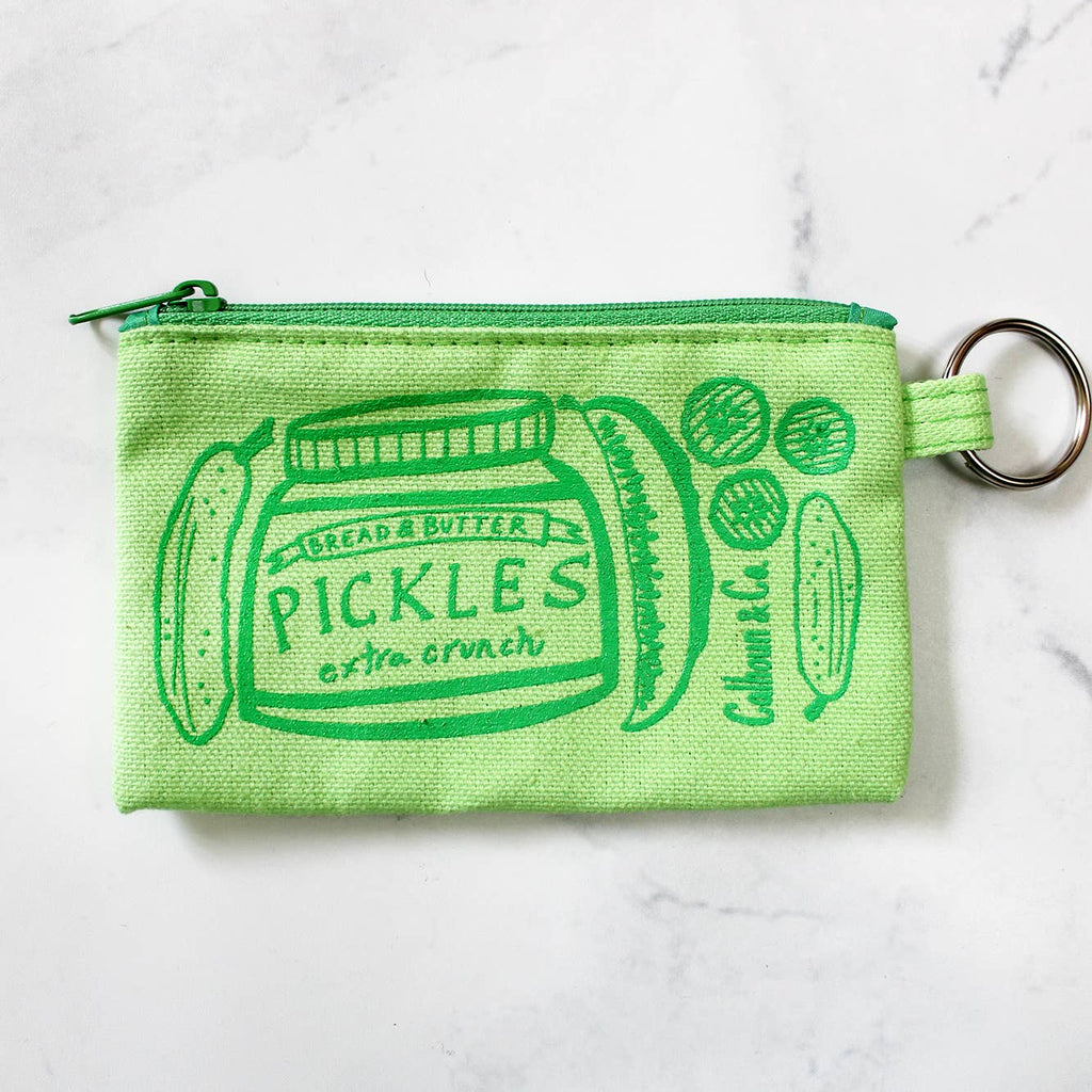 Image of coin purse with green background and image of a jar of pickles and pickles with metal key ring and zippered top. 