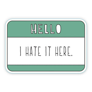 Decorative sticker in shape of Hello sticker with green and white with white text says, "Hello" and black text says, "I hate it here.". 