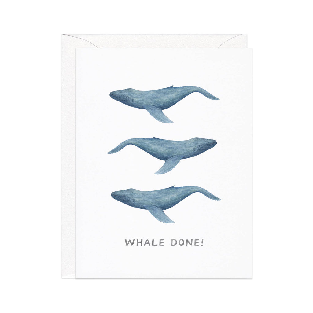 Greeting card with white background with images of three grey whales and gray text says, "Whale Done!". White envelope included. 