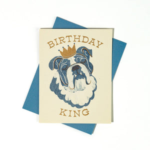 Greeting card with cream background and image of a blue and cream bull dog wearing a gold crown and gold text says, "Birthday King". Blue envelope included.