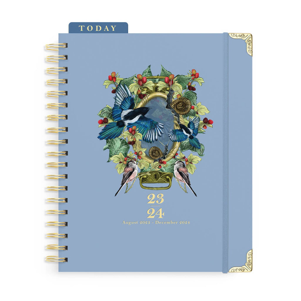 Pale blue background with images of oval mirror surrounded with flowers, birds and berries.  Gold metal corner protectors, spiral binding, and gold text says, “3-24”, “August 2023 – December 2024”. Dark blue page marker with gold text says, “Today”. 