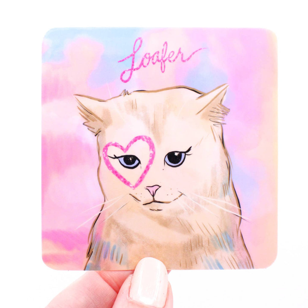 Image of a sticker with a pink and blue background and a tan cat with a pink heart drawn around the right eye and pink text says, "Loafer". 