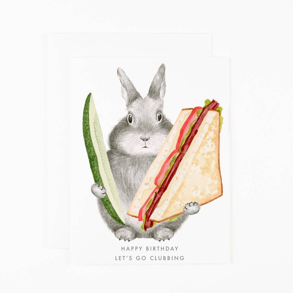 Greeting card with white background and image of a grey rabbit holding a club sandwich and a pickle spear. Gold text says, "Happy Birthday Let's go clubbing". Envelope included. 