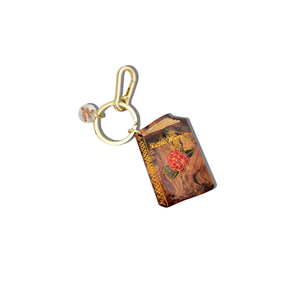 Image of a keychain charm in the image of a small book in brown with a red rose on cover and gold text says, "Little Women". Gold ring for keys and clip.