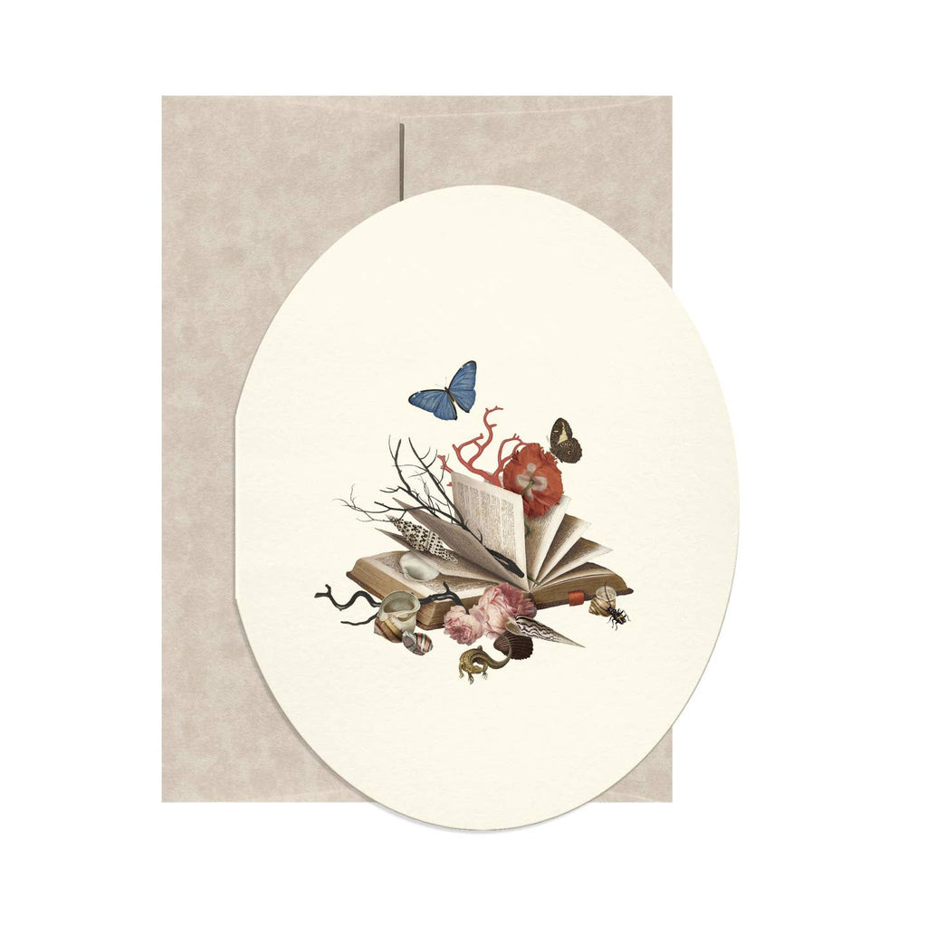 Oval greeting card with cream background and image of an open book with sea creatures coming out of the pages and a blue butterfly. Envelope included.