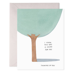 Greeting card with white background and image of a tree with black text says, "I know this day is hard for you, thinking of you". Grey envelope included. 