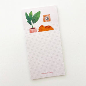 Image of note pad with image of orange cat sleeping next to a green houseplant in a pink pot with dot grid area for note writing.