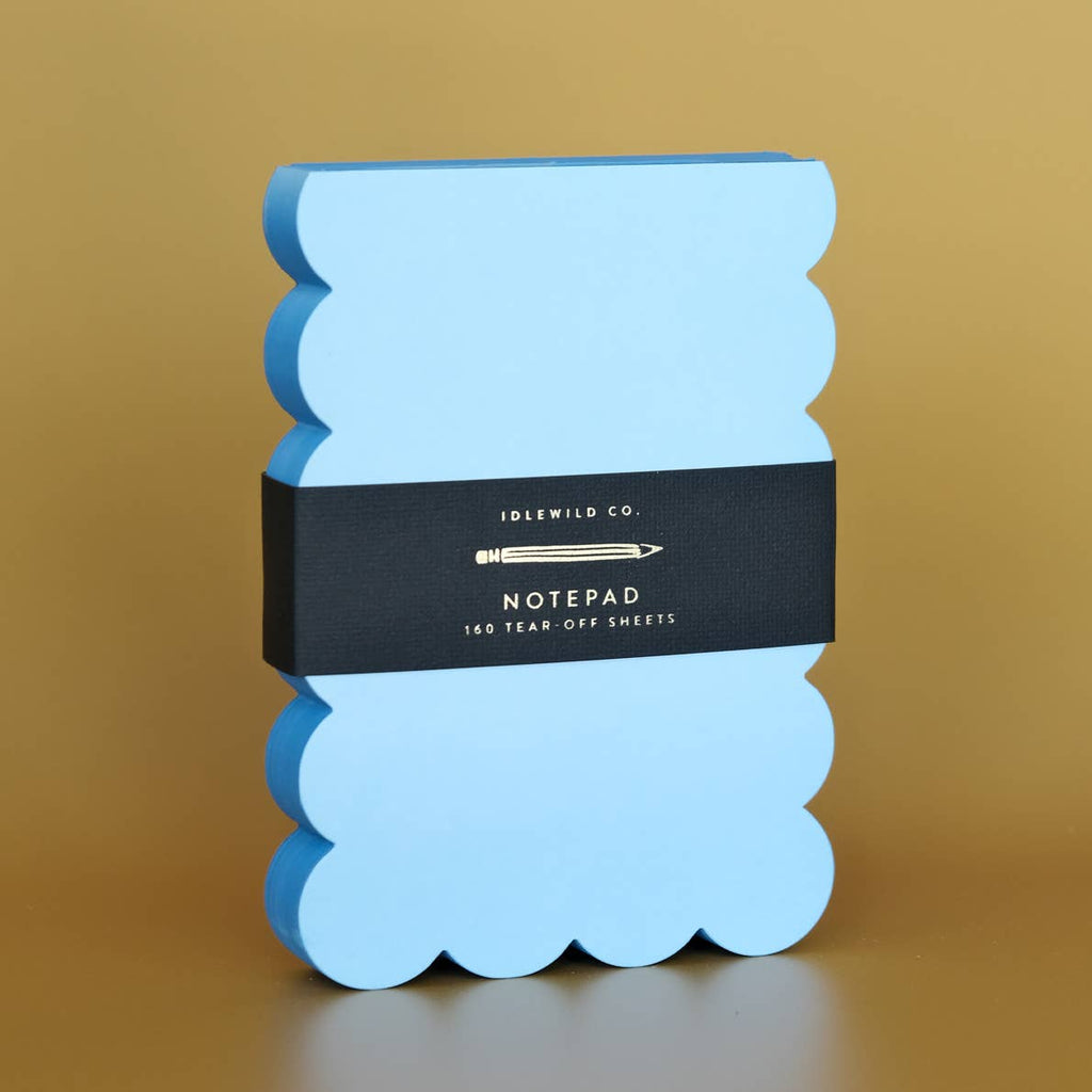 Notepad with blue pages and darker blue scalloped edges.