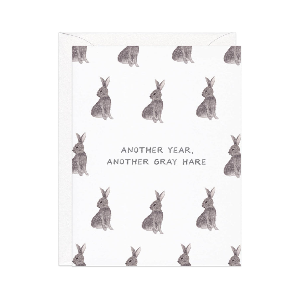 Greeting card with white background and images of gray hares  and black text says, "Another year, another gray hare". White envelope included. 