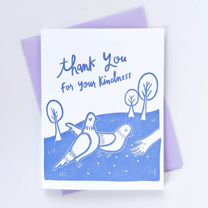 Greeting card with white background and images of two white pigeons with a hand feeding them. Blue text says, "thank you for your kindness". Lilac envelope included. 