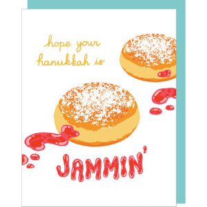 Greeting card with white background and image of tow jelly donuts with yellow text says, "Hope your hanukkah is". Red text says, "jammin'". Teal envelope included.