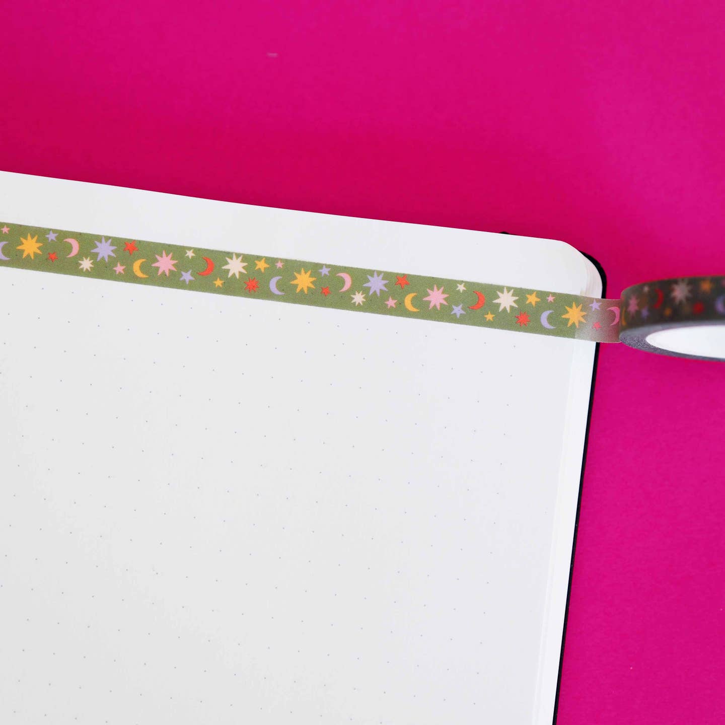Washi tape with olive green background and bursts, stars and moons in pink,cream, yellow,red and lilac. 