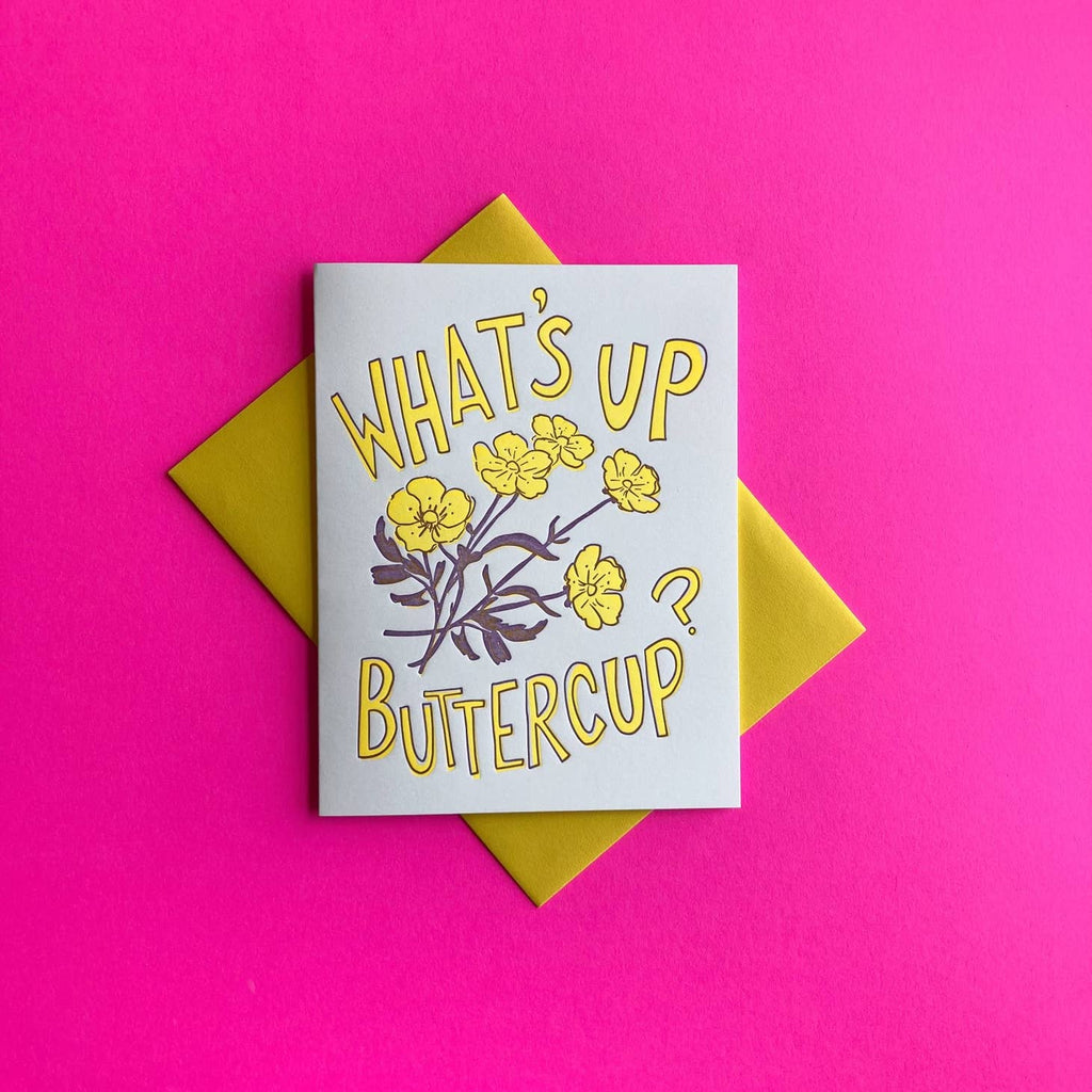 White background with yellow buttercups with purple stems and leaves. Yellow text says,”What’s up buttercup?”. Yellow envelope is included.           